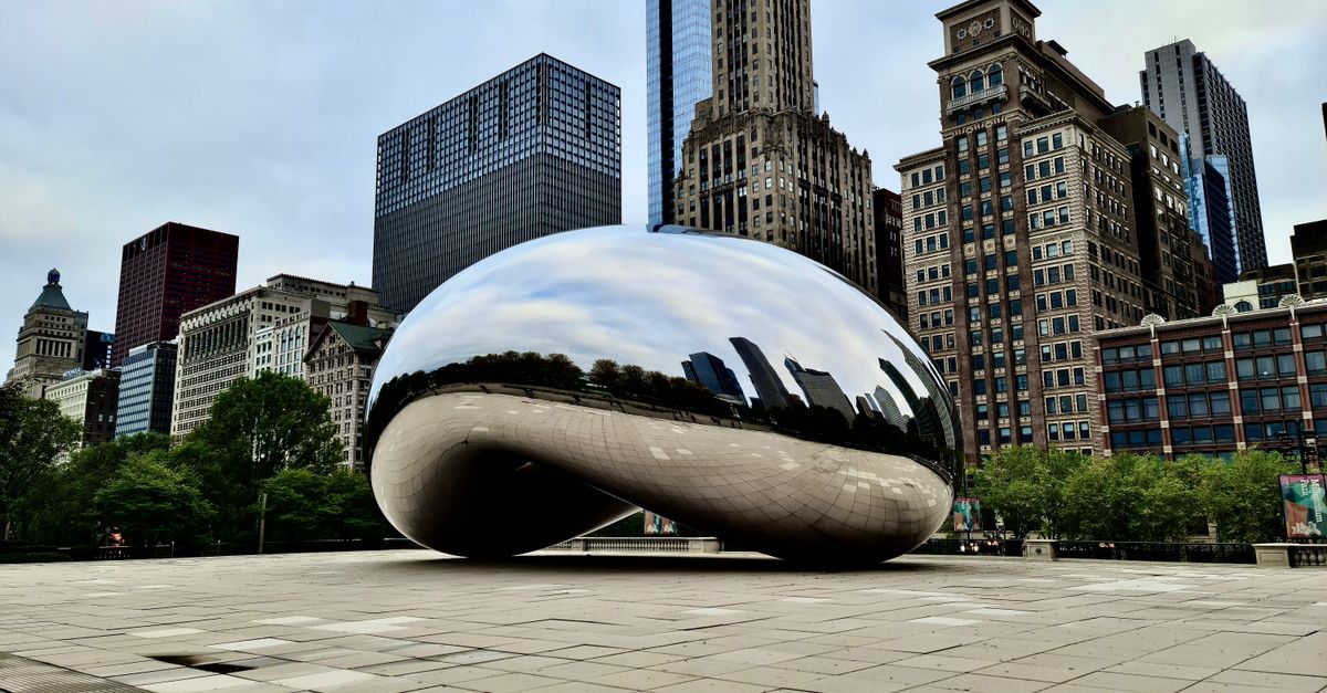 The reflective Cloud Gate sculpture in Chicago surrounded by iconic skyscrapers.